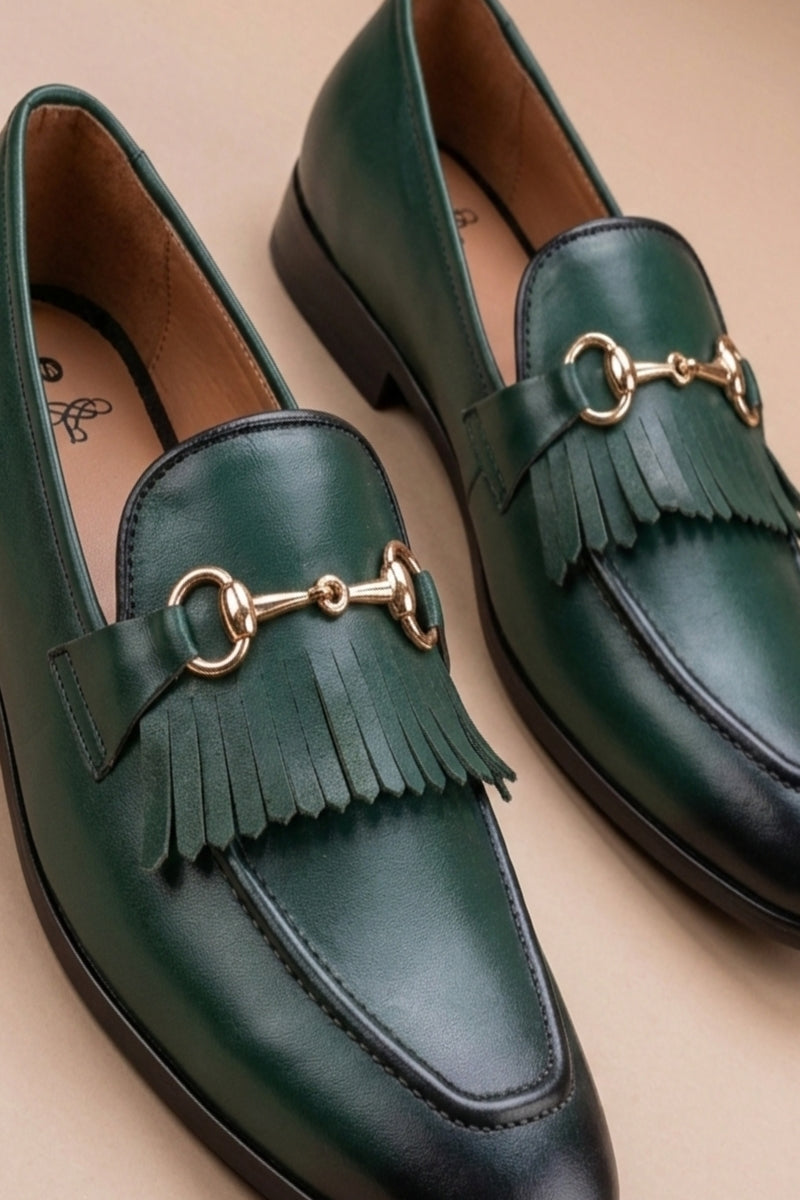 pair of green  horsebit loafers possibly made of leather or synthetic leather,featuring a gold-tone buckle detail and fringe