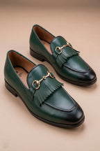 pair of green  horsebit loafers possibly made of leather or synthetic leather,featuring a gold-tone buckle detail and fringe