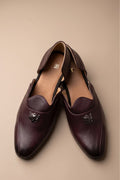 Brown glossy juttis for featuring a metallic crest embellishment