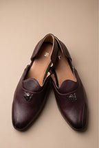 Brown glossy juttis for featuring a metallic crest embellishment