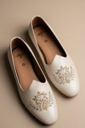 Cream colour juttis with intricate silver and crest -inspired embroidery